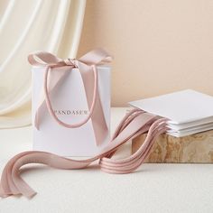 a pink ribbon tied around a white bag