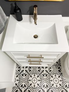 a white sink sitting under a mirror next to a gold faucet in a bathroom