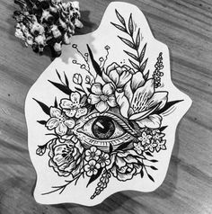 a sticker with an eye surrounded by flowers and leaves on top of a wooden table