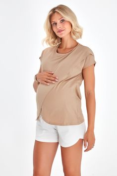 a pregnant woman wearing white shorts and a t - shirt is posing for the camera