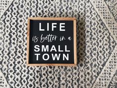 a small black and white sign that says life is better in a small town on it