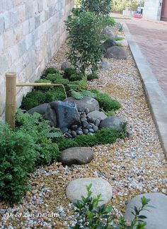 a garden with rocks and plants next to a building