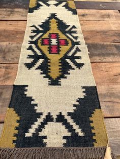 a black, yellow and white rug with fringes on top of wooden flooring