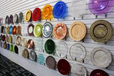 there are many plates on the wall with different colors and shapes hanging from it's sides