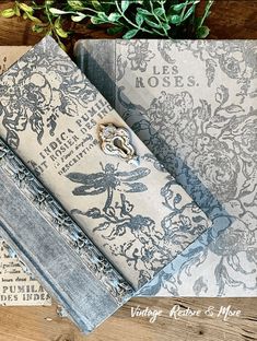 an old book is sitting on top of a wooden table next to other books and papers