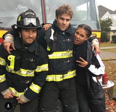 three firemen are posing for a photo in front of a fire truck with their arms around each other