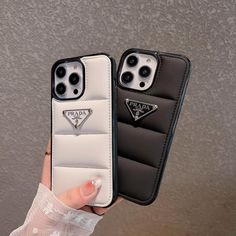 two black and white iphone cases are held up