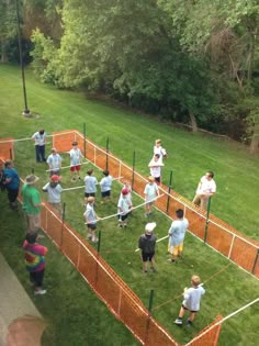 a group of people playing tennis on top of a grass covered field in front of trees