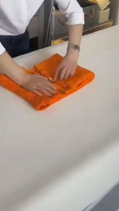 a person is cleaning an orange cloth on a table