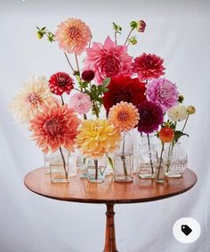 a wooden table topped with lots of vases filled with flowers on top of it