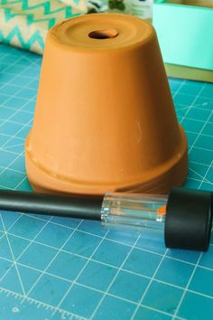 a brown vase sitting on top of a cutting board next to a black plastic pen