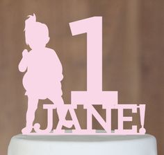 a white cake with a pink frosting number one on it and a silhouette of a girl holding a teddy bear