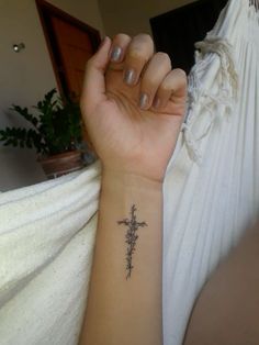 a woman's arm with a cross tattoo on the left side of her wrist