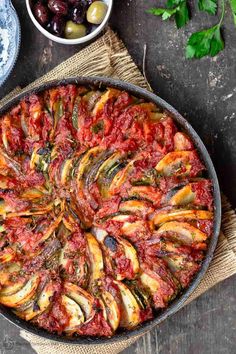 an overhead view of a baked dish with olives, tomatoes and other food items