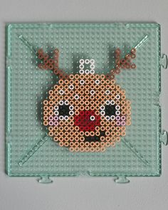 a cross stitch beaded reindeer ornament hanging on a wall