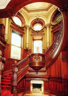 an ornate staircase with red carpet and wooden paneling