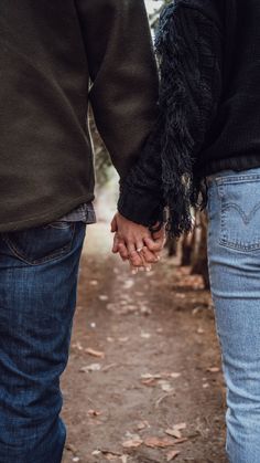 two people holding hands while walking down a path