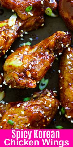 spicy korean chicken wings with sesame seeds and green onions on a black plate, ready to be eaten