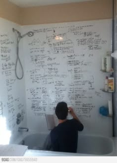 a man writing on a whiteboard in a bathtub next to a shower head