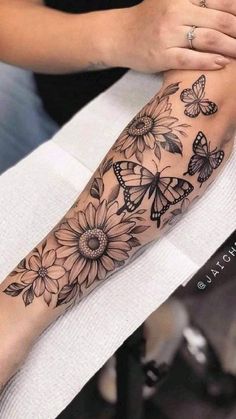 a woman is getting her tattoo done with butterflies and sunflowers on her arm