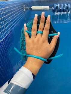 a woman's hand with pink and blue nail polish holding up a tennis racket