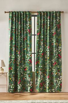 a green floral curtain with red and yellow flowers on the top, hanging in front of a window