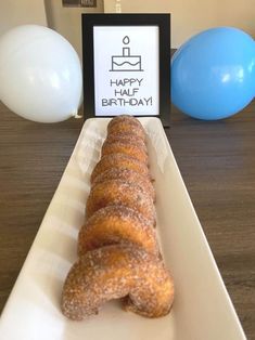 a doughnut sitting on top of a white plate next to blue and white balloons