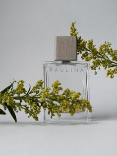 a bottle of perfume sitting on top of a table next to some flowers and leaves