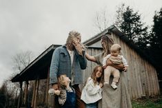 a group of people standing next to each other holding baby's hands and looking at the camera