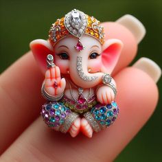 an elephant figurine is sitting on someone's finger with jewels around it