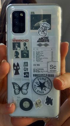 someone is holding up their phone case with stickers on it and there are other things in the back