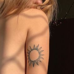 a woman with a sun tattoo on her left arm and right arm behind her back