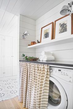 a washer and dryer in a small room with white walls, wood floors and open shelving