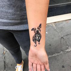 a small dog tattoo on the left wrist and right hand is shown in black ink