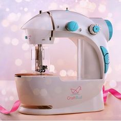 a white and blue sewing machine with pink ribbon