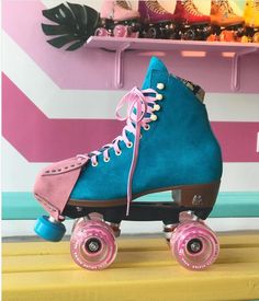 a blue roller skate with pink wheels and laces on the bottom, in front of a colorful striped wall