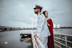 a man and woman are standing on a pier