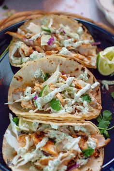 three tacos with chicken, lettuce and cilantro on a blue plate