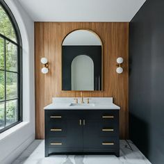 a bathroom with black and white marble countertops, gold accents and a round mirror