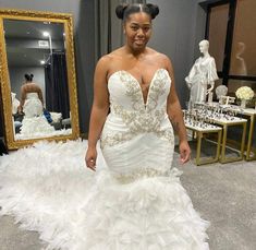 a woman standing in front of a mirror wearing a wedding dress with feathers on it