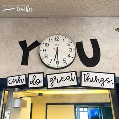 a clock mounted to the side of a wall above a sign that says you can do great things