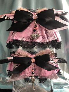 Pretty 4" wide keepsake garter is constructed of a base layer of black lace with an overlay of a glittering shades of pink with black outlined skulls and crossbones with swirls background cotton fabric and a black satin band.  Embellished with coordinating organza and satin ribbons and bows, guinnea feathers and centered with a pink rhinestone!  Finished with a dangling charm of glass beads and crystals including rhinestone set skull, spider web and skeleton key charms!  Matching tossing garter included!  Fits up to a 28" thigh comfortably. Please visit my shop to view a variety of unique garter sets! Swirls Background, Unique Garter, Thigh Garter, Skull Spider, Pink Goth, Key Charms, Satin Noir, Wedding Garters, Pink Skull