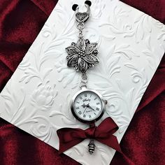 This delightfully whimsical, and fully functional, vintage style watch adds a touch of classic Victorian flair to your chatelaine! This stunning watch features many intricate details like the large floral filigree ornament, scrolled watch hands, and antique silver drop ornament that add so much elegance and charm. It also has a large vintage style clasp, so it can be easily attached or removed from your chatelaine.   The watch comes with the battery installed, just remove the white plastic guard on the side knob, turn the knob clockwise to set the time, and then push the knob in to activate the watch.   SIZING/ MEASUREMENTS   Watch face: 1 inch diameter Total length: 5 inches **Made in a smoke/pet free environment** SHOP POLICIES CANCELLATION: You can request cancellation within 24 hours o Metal Watch Accessories With Round Dial For Gift, Metal Pocket Watch With Round Dial For Gift, Metal Pocket Watch With Round Dial As Gift, Metal Pocket Watch With Round Dial, Vintage Silver Watches With Compass Design, Antique Silver Watch Accessories Gift, Antique Silver Watch Accessories For Gift, Antique Silver Watch Accessories As Gift, Elegant Silver Metal Pocket Watch