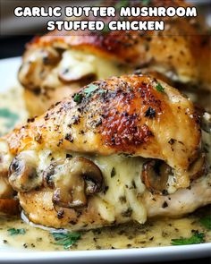 two pieces of chicken covered in mushrooms and sauce on a white plate with the words garlic butter mushroom stuffed chicken