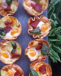 many small pastries are arranged on a tray next to some ferns and flowers in the background