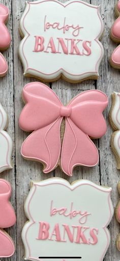 some pink and white decorated cookies on a wooden table with the words baby banks written on them