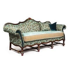 an ornate couch with leopard print on the back and blue pillows, against a white background