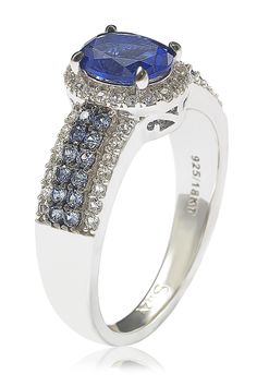 A blue sapphire halo ring features a sparkling pave encrusted band for luxe glamour. Sterling silver oval cut sapphire halo and pave sapphire embellished band ring with hidden brown diamond accent. Approx. 10mm L x 5mm W ring face. ImportedPlease note: Diamond weight may not be exact. Dazzling Sapphire Ring With Pave Setting, Oval Blue Diamond Ring With Pave Setting, Anniversary Tanzanite Halo Ring, Oval Sapphire Ring With Pave Setting, Oval Halo Ring With Pave Setting For Anniversary, Sapphire Halo Ring With Diamond Accents For Anniversary, Oval Sapphire Ring With Pave Setting For Anniversary, Classic Oval Sapphire Ring With Pave Setting, Sapphire Ring With Pave Setting For Anniversary