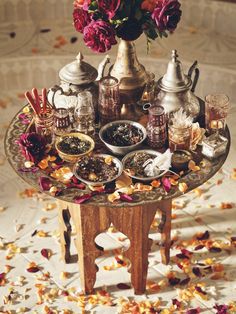 a table topped with lots of food and vases filled with flowers on top of it