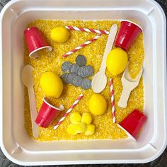 a plastic tray filled with yellow sand and toys